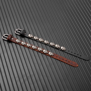 Detail of black and brown punk leather bracelets with silver skull studs and buckle