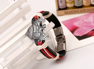 Makroaufnahme von geflochtenem Lederarmband mit Vintage-Silberfisch-Anhänger auf Mini-Bank