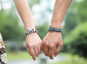 Nahaufnahme von Paaren, die handgewebte Armbänder mit ethnischen Fisch-Anhängern tragen