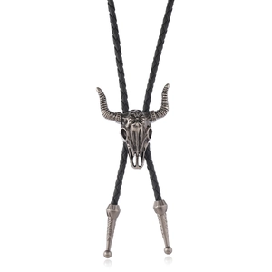Western vintage bolo tie featuring an antique silver bull skull pendant on black braided cord