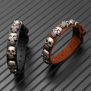 Detail of punk leather bracelet showing vintage metal skulls and buckle closure
