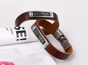 Detail of vintage brown leather bracelets with Best Friend engraved silver plates