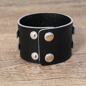 Close-up of a wide black leather punk bracelet with four silver metal snap buttons