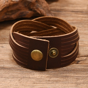 Detail of dark brown braided leather bracelet with vintage bronze snap on wooden background