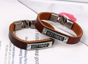 Close-up of vintage brown leather bracelets featuring engraved BEST FRIEND metal plates