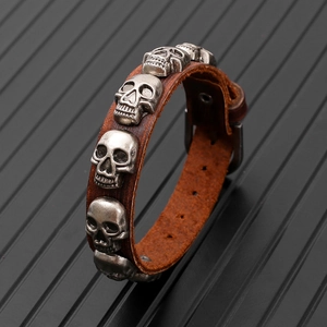 Detail of punk leather bracelet showing silver skulls and adjustable metal buckle