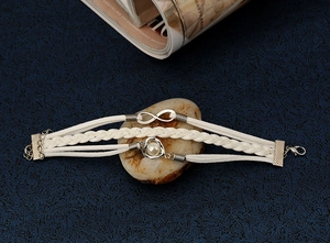 Détail d'un bracelet tressé multicouche avec symbole infini et breloque perle en cœur