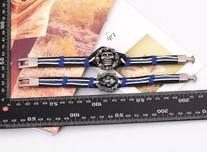 Detail view of woven leather bracelets with skull and lion head alloy charms with ruler