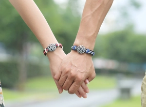 Ethnic braided leather couple bracelets with vintage metal pendants shown on hands