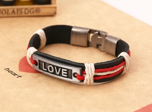 Detail eines handgefertigten Lederarmbands mit silberner LOVE-Platte und Flechtschnüren