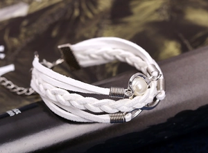 Détail d'un bracelet tressé blanc multicouche avec perle et symbole de l'infini