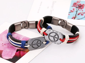 Détail de bracelets en cuir tressé avec plaques en métal symbole de paix et cordes
