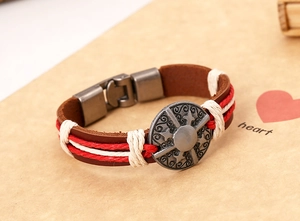 Detailed macro of vintage brown leather bracelet with braided cord and round totem buckle