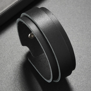 Close-up of double-wrap black leather bracelet with metallic snap button and gray edges