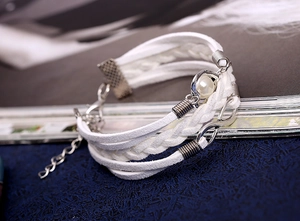 Détail d'un bracelet multicouche en cuir tressé blanc avec symbole infini et perle