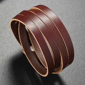 Detail of dark brown leather wrap bracelet with silver metal snap button and natural texture