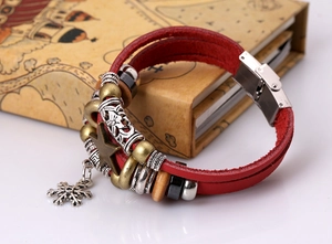 Detail of red multilayer leather bohemian bracelet with metal charms on vintage book