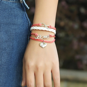 Gros plan du bracelet en cuir tressé rose avec breloques Infinity, Love et Sister