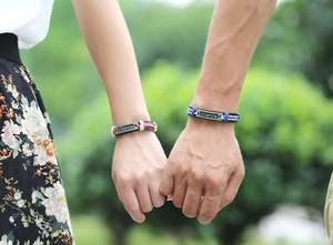 Détail de bracelets de couple tressés avec plaque silence gravée portés au poignet