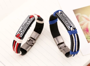 Macro detail of 'believe' engraved metal plate on woven leather couple bracelet