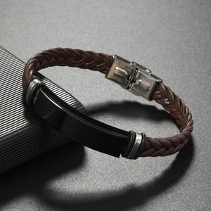 Macro detail of men's braided leather bracelet with polished black stainless steel plate