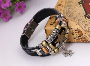 Detail view of multi-layer leather bracelet featuring bronze star and snowflake charms