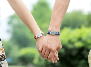Close-up of matching woven couple bracelets with sun and moon engraved metal charms