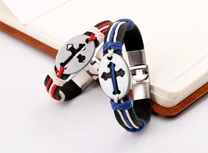 Detail of vintage leather bracelets with cross metal charms on a classic notebook