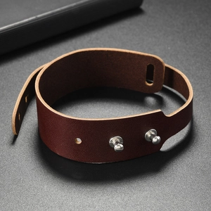 Macro detail of dark brown double-wrap leather bracelet with silver metal button fasteners