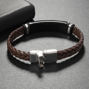 Macro shot of men's brown braided leather bracelet with black stainless steel ID plate