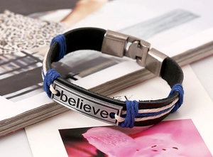 Macro detail of braided leather bracelet with engraved believe silver metal plaque