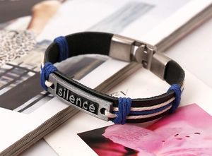 Détail d'un bracelet en cuir tressé avec gravure silence et fermoir en métal sur magazine