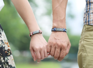 Macro shot of hand-woven couple bracelets with metallic plate engraved with Believe