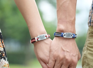 Macro detail of braided leather couple bracelets with fish engraved metal plates