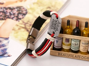 Macro view of multi-layer braided leather bracelet with fish symbol metal plate and clasp