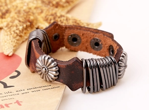Macro shot of brown leather punk bracelet featuring vintage silver flower studs and snaps
