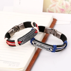 Pair of braided leather BELIEVE bracelets on a notebook with vintage metal plates
