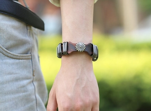 Macro detail of punk vintage leather bracelet featuring a metal sunflower crest design