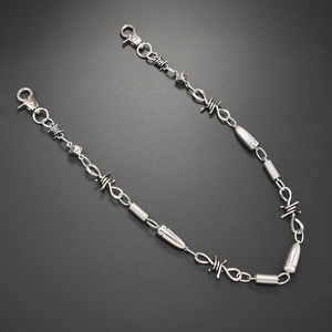 Punk style silver pants chain featuring barbed wire motifs and dice charms on a dark background