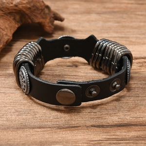 Detail of punk leather bracelet with metal rings and vintage silver medallion on wood