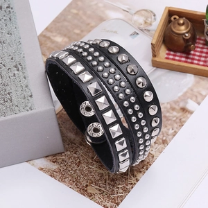 Detail of black leather punk bracelet with silver metal rivets and adjustable snap buttons