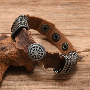Detail of adjustable brown leather cuff with star metal buckle on rustic wood
