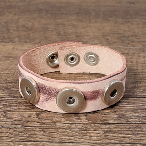 Detail of vintage leather snap bracelet with three silver metal bases on wood background