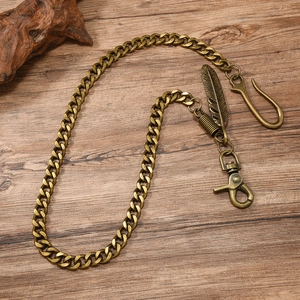 Vintage bronze punk wallet chain with feather pendant on rustic dark wood background