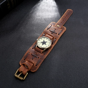 Detail of vintage brown leather cuff watch featuring star motif and cross-stitch seams