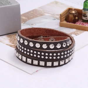 Macro detail of dark brown leather triple wrap bracelet featuring punk style rivets