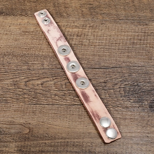 Adjustable vintage leather bracelet with five silver snap buttons on a wooden background