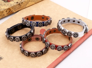 Close-up of leather bracelets in five colors with metal cross studs on paper background