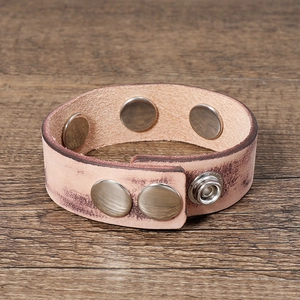 Vintage neutral beige leather bracelet with snap fastener and metal rivets on wood surface