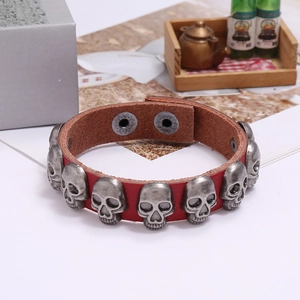 Detail of punk leather bracelet with silver skull charms and double snap button clasp